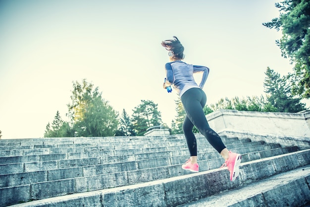 Junge Frau, die Sport treibt und die Treppe hochläuft.