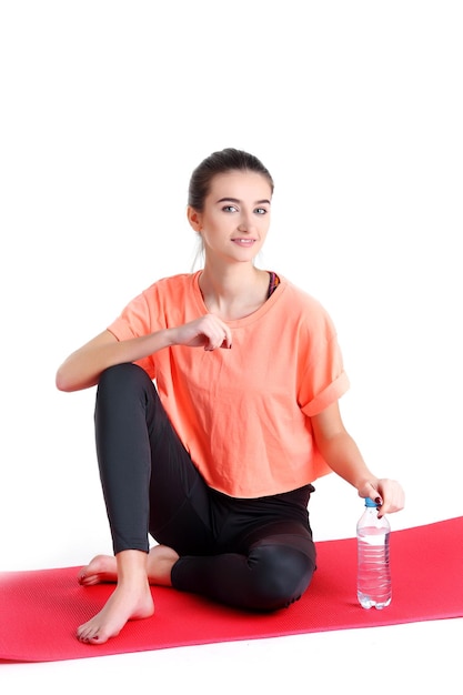 Junge Frau, die Sportkleidung trägt, trinkt Wasser