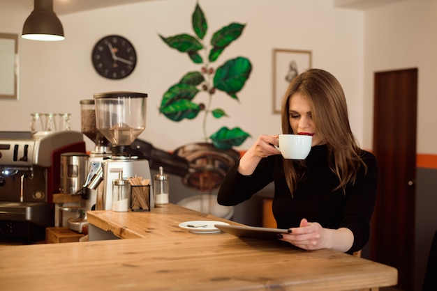 Junge Frau, die Tablet-Computer in einem Café verwendet.