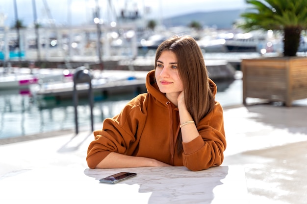 Junge Frau, die Tag in einem Straßencafé im Yachthafen in Porto Montenegro genießt