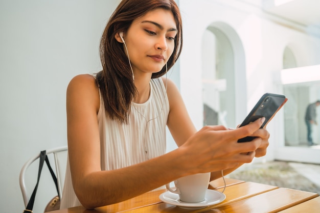 Junge Frau, die Telefon am Kaffeehaus benutzt