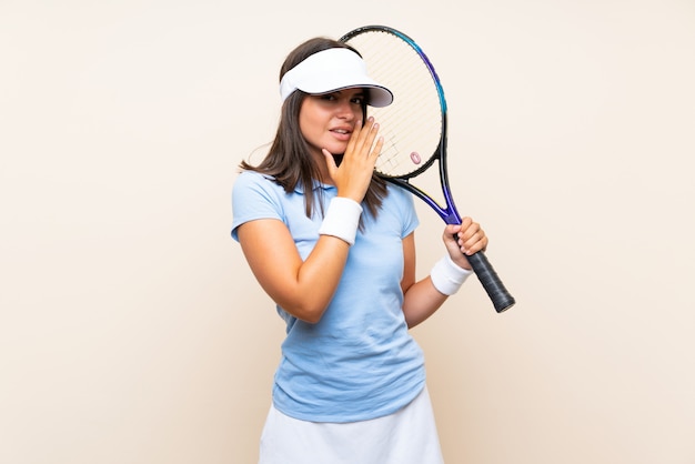 Junge Frau, die Tennis über der lokalisierten Wand flüstert etwas spielt