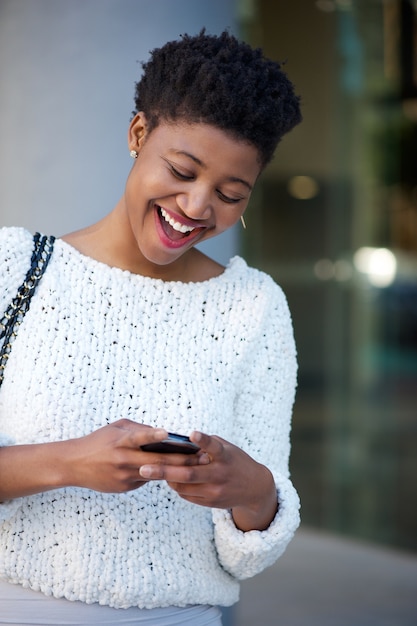 Junge Frau, die Textnachricht auf Mobiltelefon lacht und liest