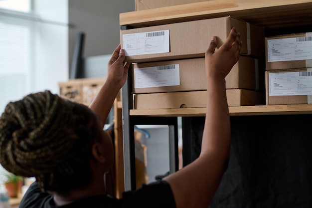 Junge Frau, die verpackten Karton mit Paket auf Stapel legt