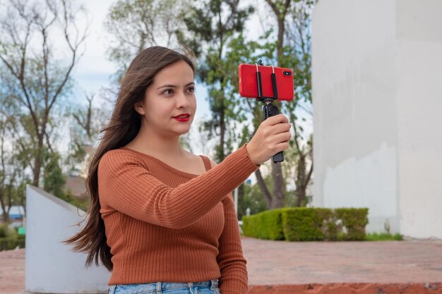 Junge Frau, die Video-Vlog mit Smartphone und kardanischem Stabilisator im Freien macht und auf den Straßen vloggt