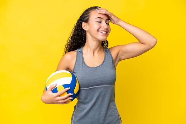 Junge Frau, die Volleyball spielt, isoliert auf gelbem Hintergrund, lächelt viel