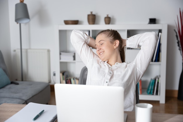 Junge Frau, die vor Laptop sich entspannt