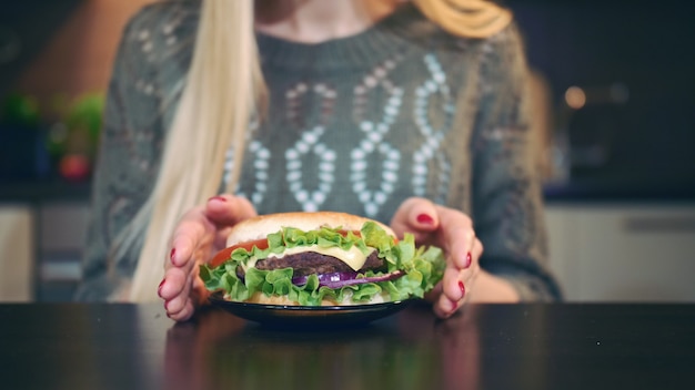 Junge Frau, die vorbereitet, einen Hamburger zu essen