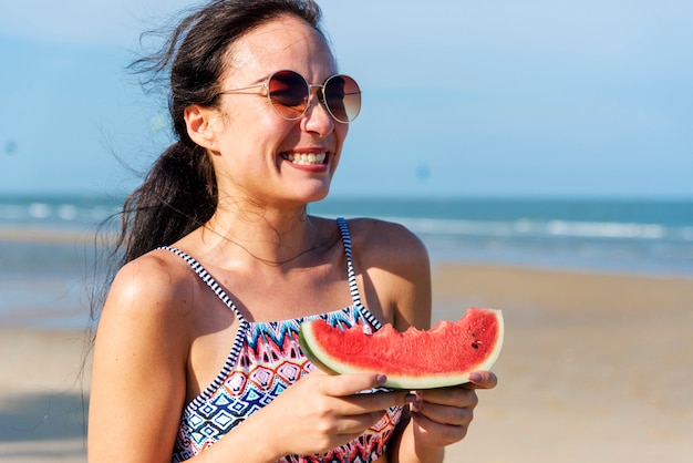 Junge Frau, die Wassermelone am Strand hält