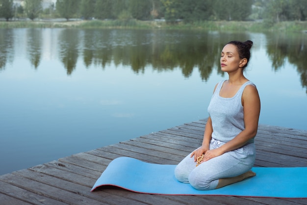 junge Frau, die Yoga am See tut