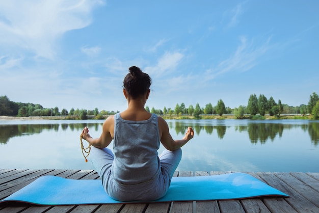 junge Frau, die Yoga am See tut