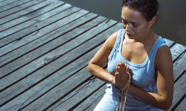 junge Frau, die Yoga am See tut