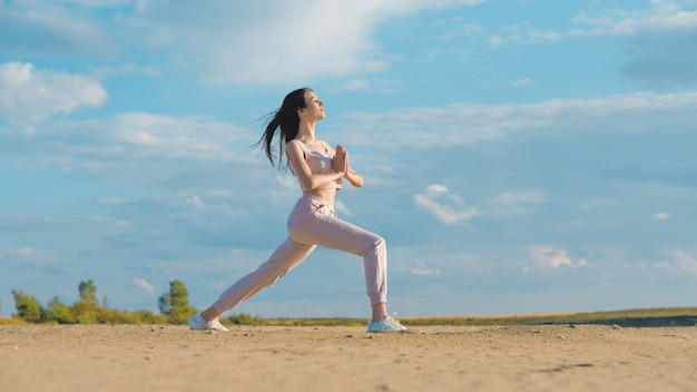 Junge Frau, die Yoga am Strand tut