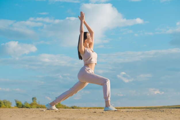 Junge Frau, die Yoga am Strand tut