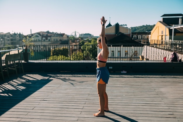 Junge Frau, die Yoga auf dem Dach eines Gebäudes praktiziert