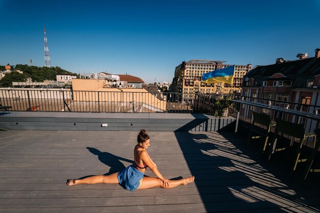 Junge Frau, die Yoga auf dem Dach eines Gebäudes praktiziert