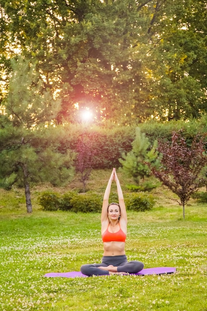 Junge Frau, die Yoga im Park praktiziert