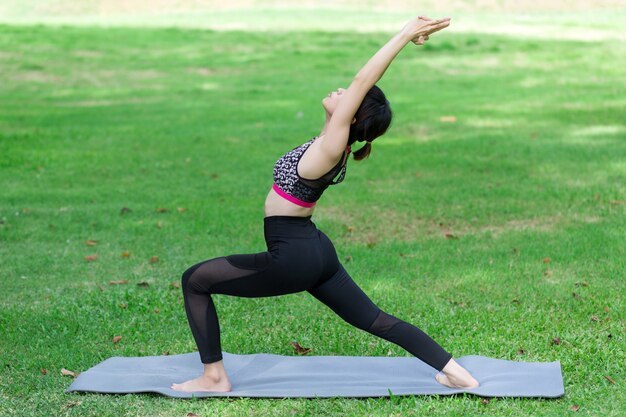 Junge Frau, die Yoga im Park tut