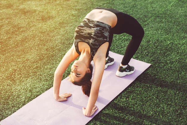 Junge Frau, die Yoga im Stadion tut