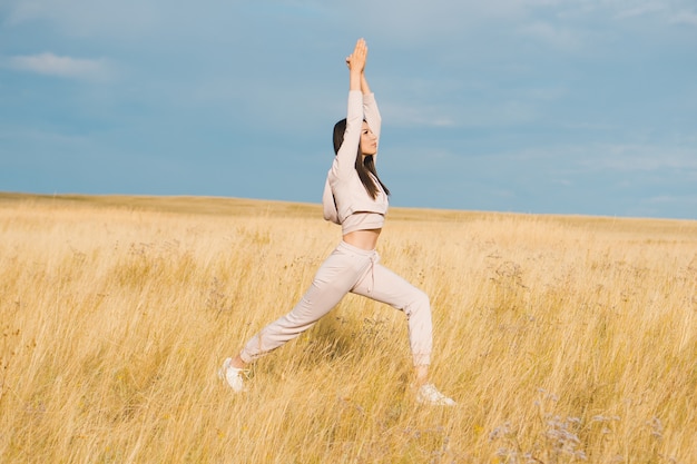 Junge Frau, die Yoga im Weizenfeld tut