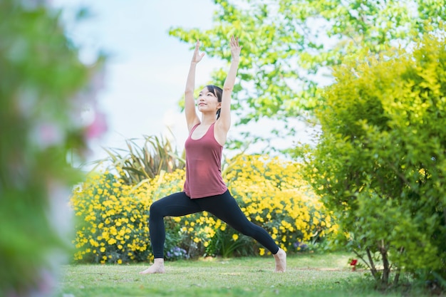 Junge Frau, die Yoga in einem grünen Park am schönen Tag tut