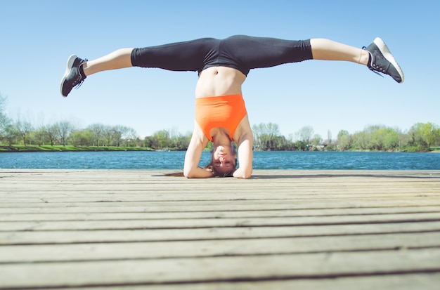 Junge Frau, die Yoga Position nahe dem See macht