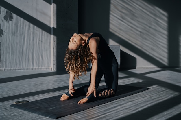 Foto junge frau, die yoga praktiziert, posiert in einem städtischen hintergrund an einem sonnigen tag