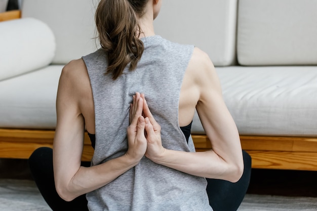 Junge Frau, die Yoga sitzt in der Übung zu Hause tut