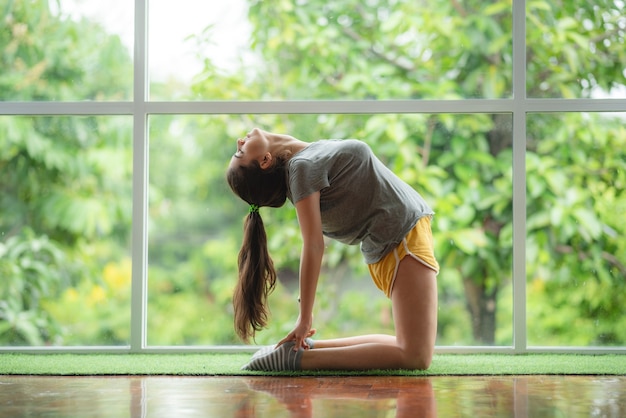 Junge Frau, die Yoga zu Hause praktiziert