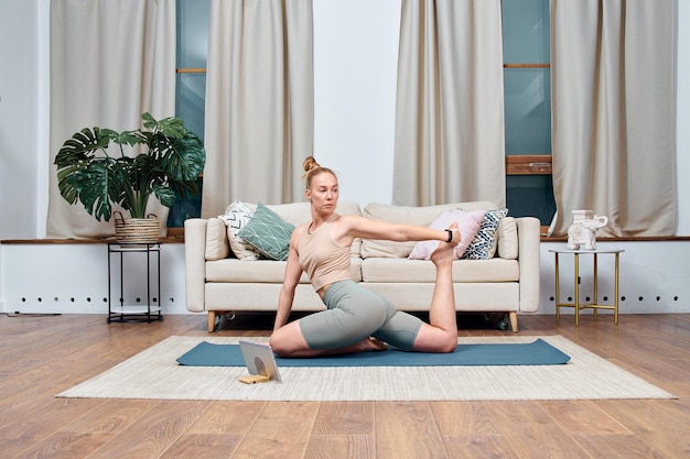 Foto junge frau, die yogaübungen in einem raum zu hause macht