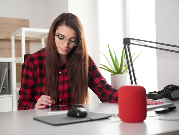 Junge Frau, die zu Hause an einem Desktop-PC und einem digitalen Tablet arbeitet