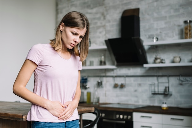 Foto junge frau, die zu hause bauchschmerzen hat