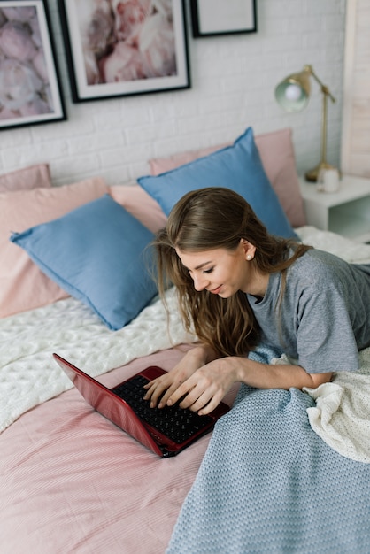 Junge Frau, die zu Hause im Bett studiert