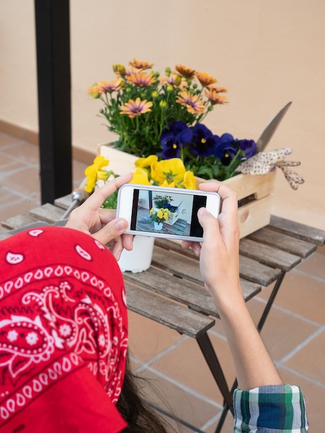 Junge Frau, die zu Hause im Garten arbeitet und Fotos zu Blumen macht