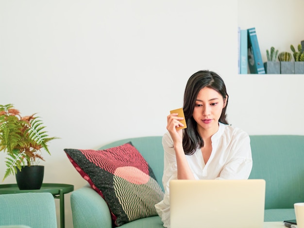 Junge Frau, die zu Hause online mit Kreditkarte und Laptop einkauft