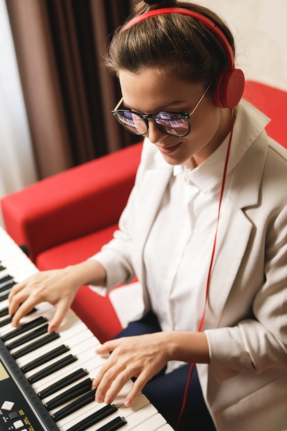 Junge Frau, die zu Hause Synthesizer spielt