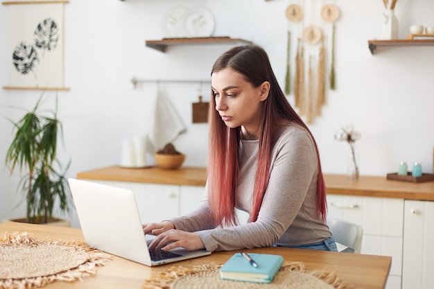 Junge Frau, die zu Hause Text auf dem Laptop schreibt, Fernunterricht. Freiberufliche Tätigkeit. Studenten online unterrichten.