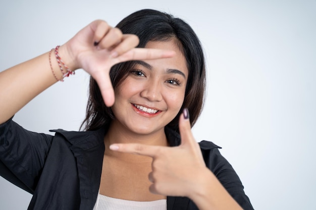 Junge Frau, die zwischen den Fingern hervorschaut, die einen Rahmen bilden