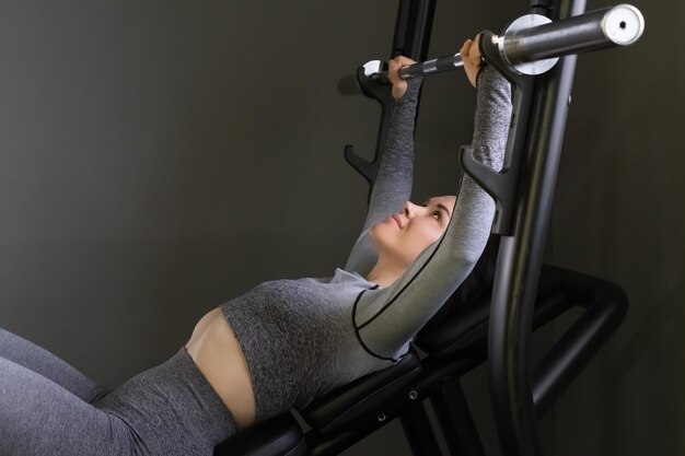 Junge Frau drückt die Langhantel im Fitnessstudio in hoher Qualität Foto