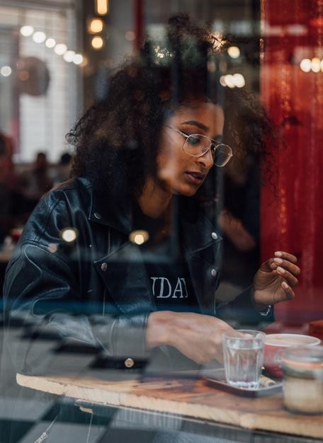 Junge Frau durch das Fenster im Café gesehen
