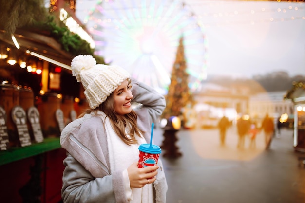 Junge Frau entspannt Kaffeetrinken in Festive Christmas fair Winterurlaub Lichter herum