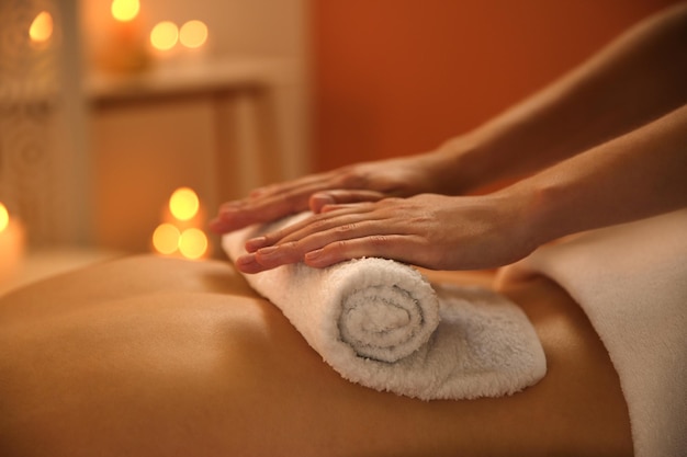Junge Frau erhält eine heiße Handtuchmassage im Spa-Salon in Nahaufnahme