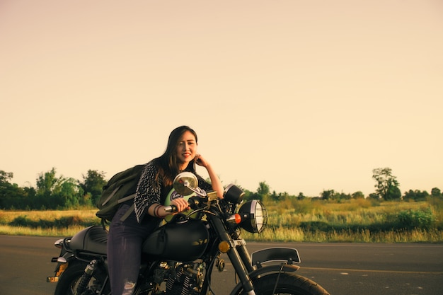 Junge Frau fährt mit dem Motorrad auf die Straße und genießt die Freiheit und den aktiven Lebensstil.