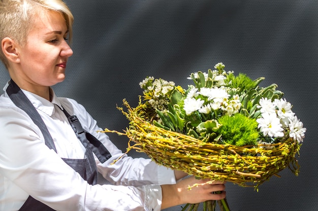 Junge Frau Floristin mit einem Blumenstrauß auf grauem Hintergrund Nahaufnahme