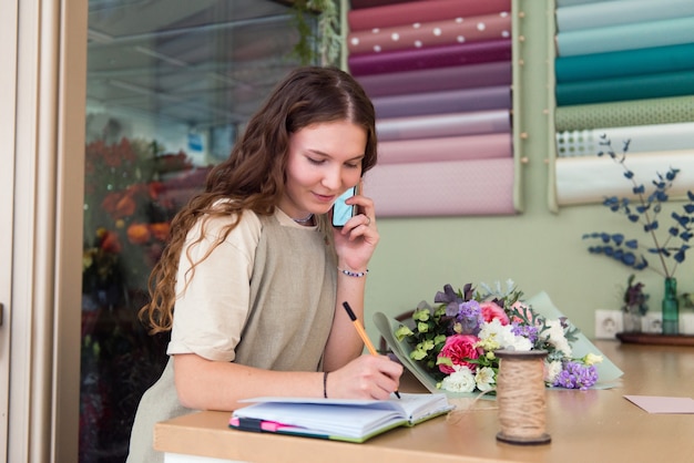 junge Frau Floristin nimmt eine Bestellung für einen Blumenstrauß Blumenladen Arbeitsplatz Lebensstil