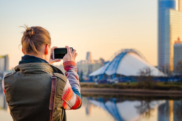 Junge Frau fotografiert die Stadt auf einem Smartphone