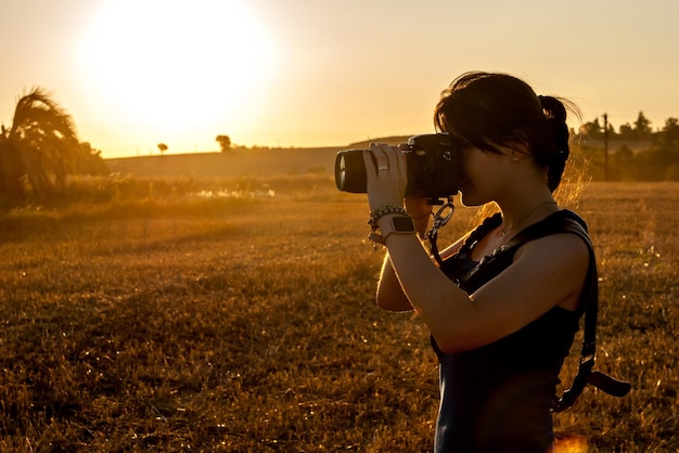 Junge Frau fotografiert in einem Sojabohnenfeld bei Sonnenuntergang