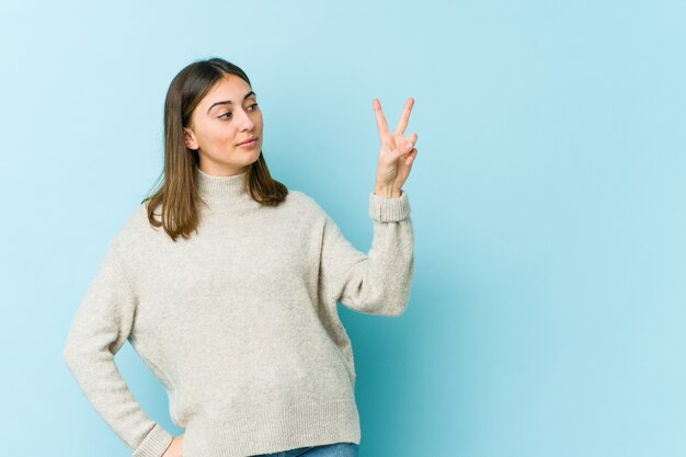 Junge Frau freudig und sorglos, ein Friedenssymbol mit den Fingern zeigend