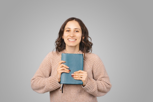 Junge Frau freut sich über ihren neuen Planer Porträt auf grauem Hintergrund