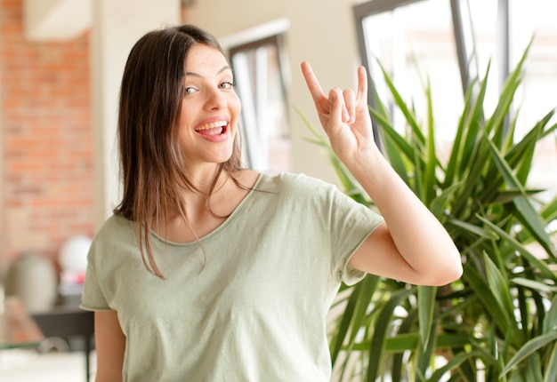 Junge Frau fühlt sich glücklich Spaß selbstbewusst positiv und rebellisch machen Rock oder Heavy Metal Zeichen mit der Hand